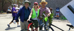 Three smiling people in front of their bicycles