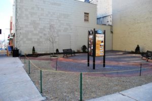 A street corner showing a parklet with shrubbery and benches